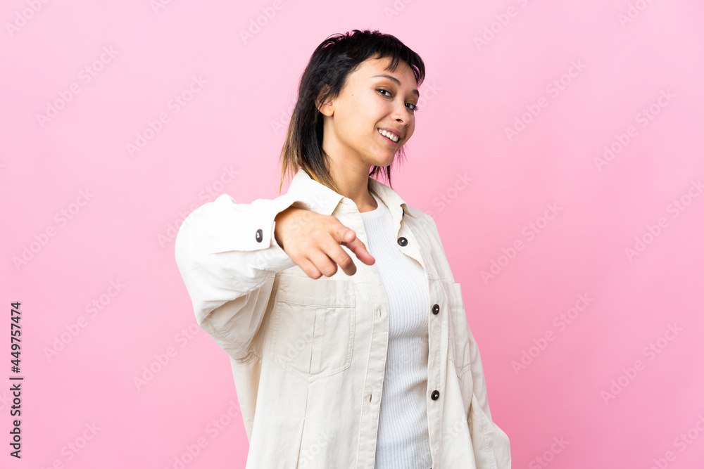 Young Uruguayan woman over isolated pink background pointing front with happy expression Young Uruguayan woman over isolated pink background pointing front with happy expression