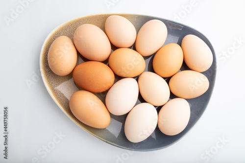 Pile of colored chicken eggs on plate isolated on white background. top view, close up.