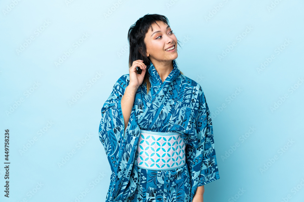 Young woman wearing kimono over isolated blue background thinking an idea Young woman wearing kimono over isolated blue background thinking an idea