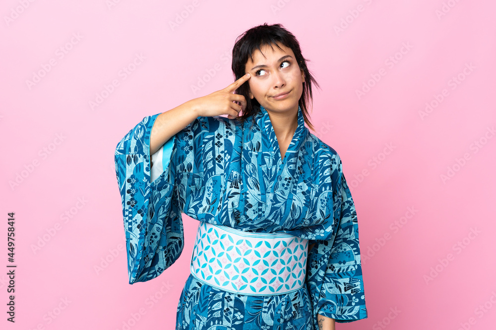 Young woman wearing kimono over isolated blue background making the gesture of madness putting finger on the head Young woman wearing kimono over isolated blue background making the gesture of madness putting finger on the head