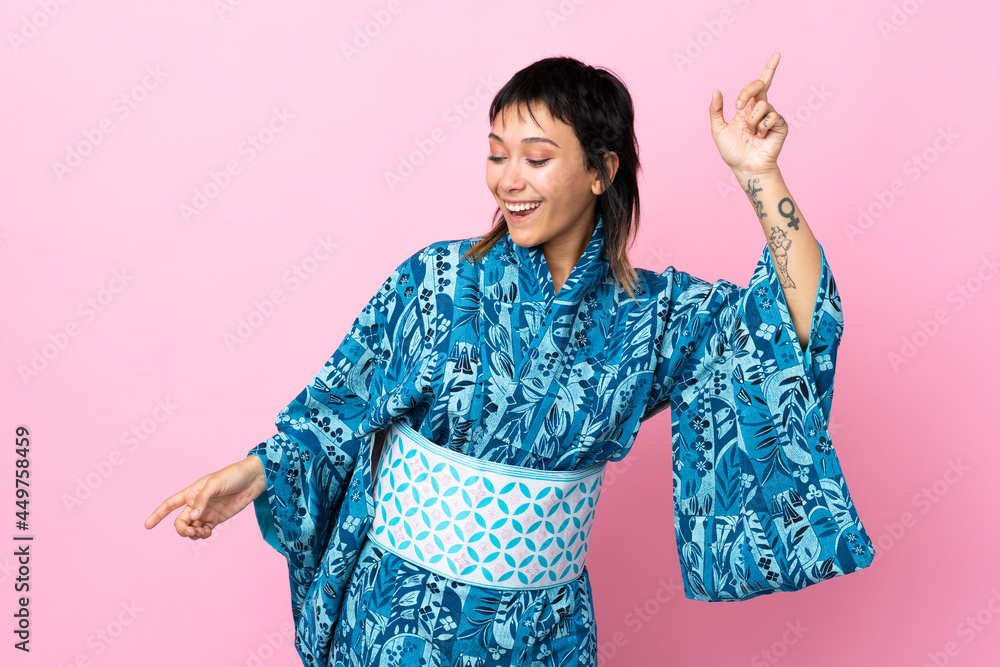 Young woman wearing kimono over isolated blue background pointing finger to the laterals and happy Young woman wearing kimono over isolated blue background pointing finger to the laterals and happy