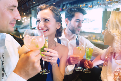 Men and women at the counter of a bar enjoying their drinks, laughing and having fun