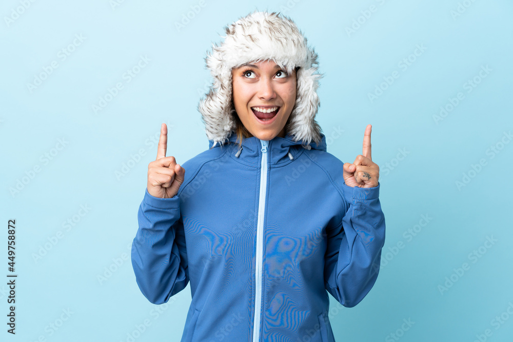 Young Uruguayan girl with winter hat isolated on blue background pointing with the index finger a great idea Young Uruguayan girl with winter hat isolated on blue background pointing with the index finger a great idea
