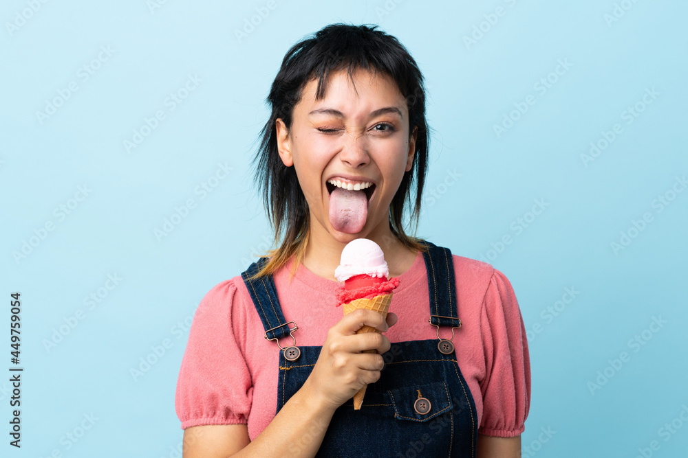 Young Uruguayan girl holding a cornet ice cream over isolated blue background Young Uruguayan girl holding a cornet ice cream over isolated blue background