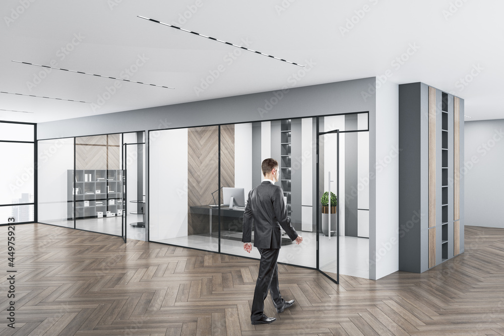 Businessperson walking in modern concrete glass office interior with daylight, equipment and wooden flooring. Workplace design concept. Businessperson walking in modern concrete glass office interior with daylight, equipment and wooden flooring. Workplace design concept.