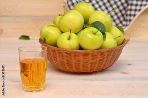a glass of apple juice and a basket of apples on the table
