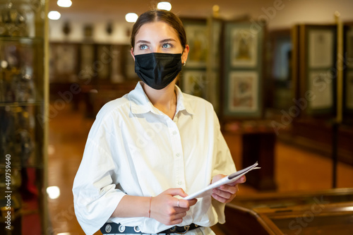 Young woman wearing face mask observing artworks in museum