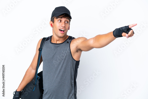 Young sport caucasian man with sport bag isolated on white background pointing away