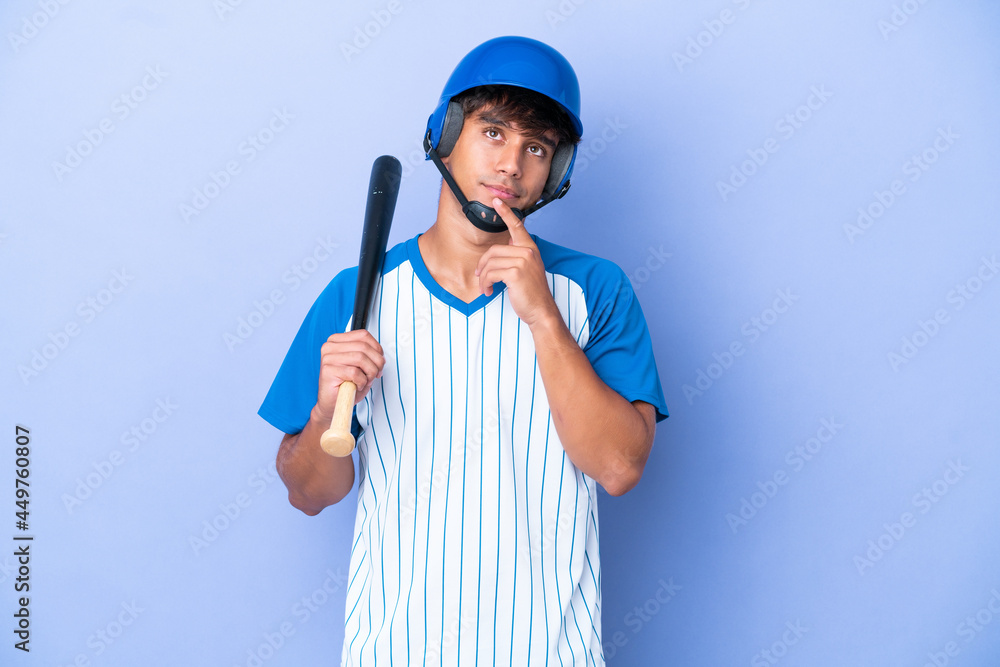 Baseball caucasian man player with helmet and bat isolated on blue background having doubts while looking up Baseball caucasian man player with helmet and bat isolated on blue background having doubts while looking up