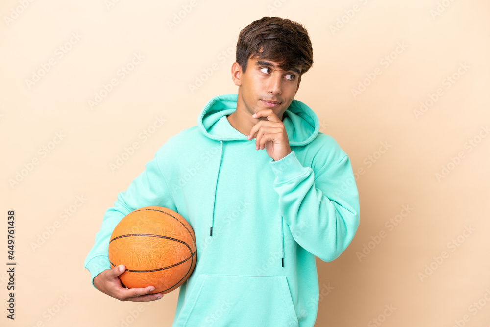 Handsome young basketball player man isolated on ocher background having doubts and thinking