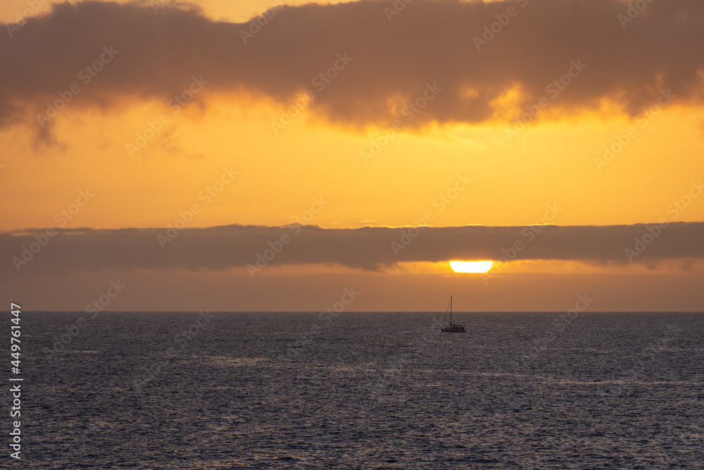 sunset over the sea with a boat at the horizon