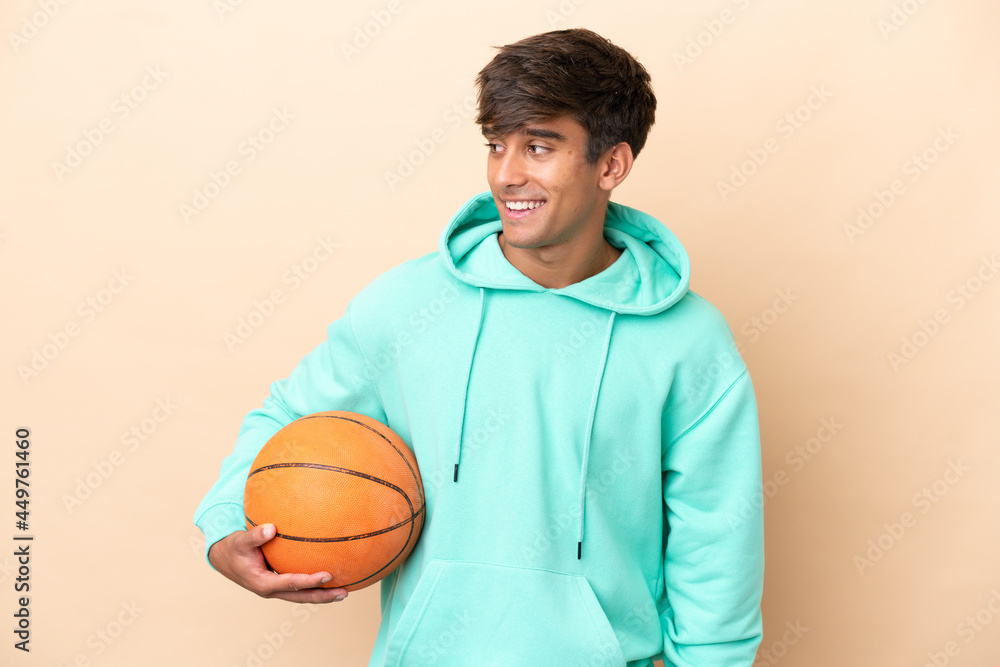 Handsome young basketball player man isolated on ocher background looking to the side and smiling