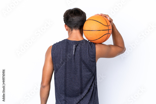 Young caucasian man isolated on white background playing basketball in back position © luismolinero
