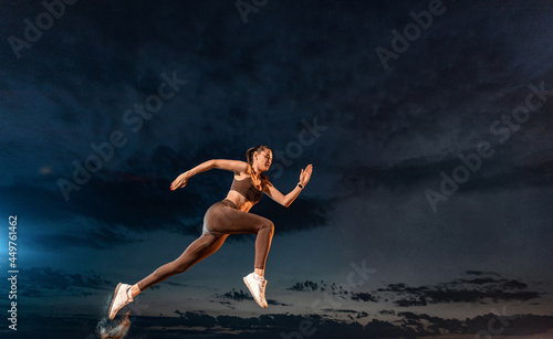 Sprinter run. Strong athletic woman running on black background wearing in the sportswear. Fitness and sport motivation. Runner concept.