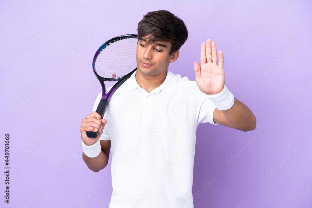 Handsome young tennis player man isolated on ocher background making stop gesture and disappointed Handsome young tennis player man isolated on ocher background making stop gesture and disappointed