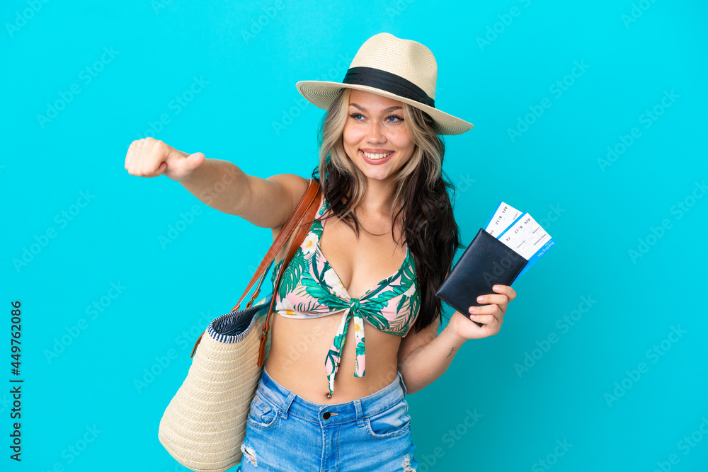 Teenager Russian girl in bikini holding a passport isolated on blue background giving a thumbs up gesture Teenager Russian girl in bikini holding a passport isolated on blue background giving a thumbs up gesture