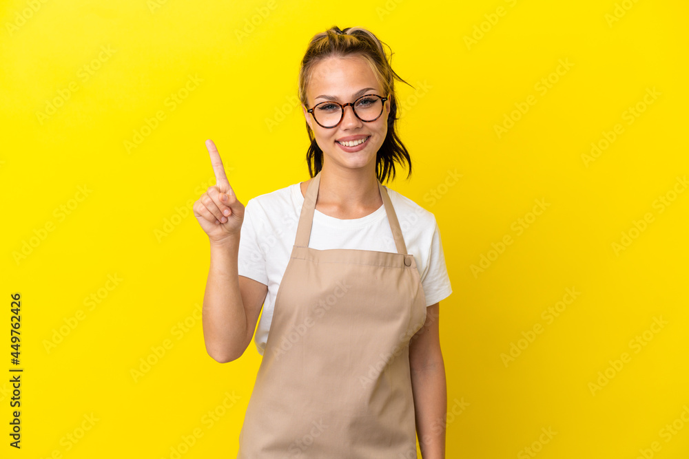 Restaurant waiter Russian girl isolated on yellow background showing and lifting a finger in sign of the best Restaurant waiter Russian girl isolated on yellow background showing and lifting a finger in sign of the best