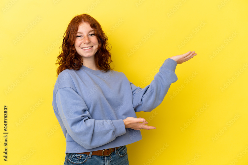 Teenager reddish woman isolated on yellow background extending hands to the side for inviting to come Teenager reddish woman isolated on yellow background extending hands to the side for inviting to come