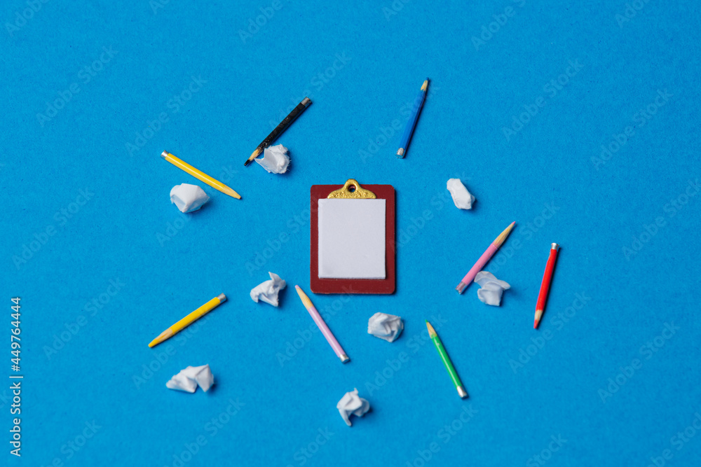 Board and pencils with crumpled papers on blue background Board and pencils with crumpled papers on blue background