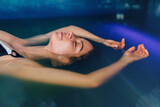 Beautiful woman floating in tank filled with dense salt water used in meditation, therapy, and alternative medicine. .