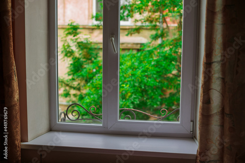 window frame view from the inside white windowsill foreground and green garden foliage outside scenic environment space