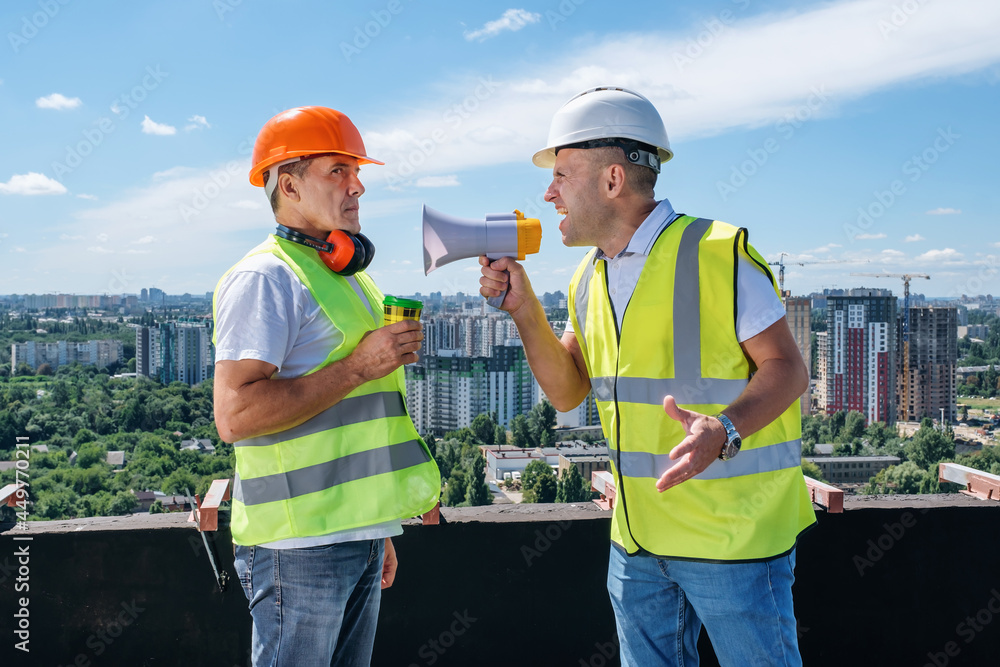 Angry boss yelling in megaphone at his builder because he made mistake on construction on the urban background Angry boss yelling in megaphone at his builder because he made mistake on construction on the urban background