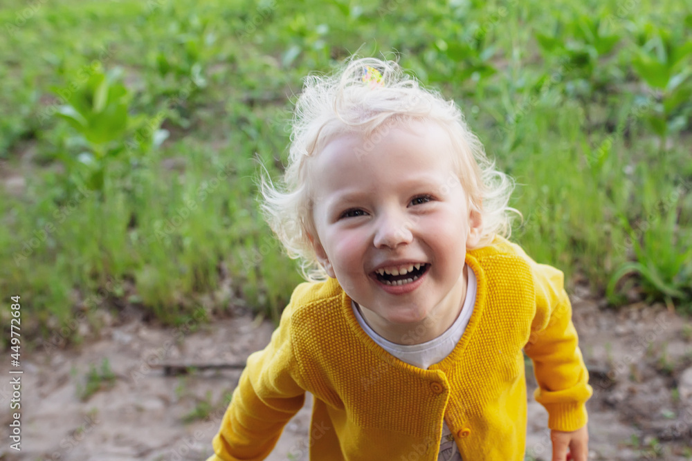 Close-up portrait happy girl in yellow jacket looks up. cheery smart clever child smiles raising face to mother Close-up portrait happy girl in yellow jacket looks up. cheery smart clever child smiles raising face to mother