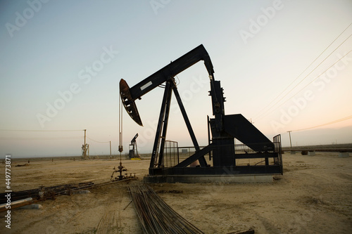 Silhouette of pump jack in oil field at sunset photo