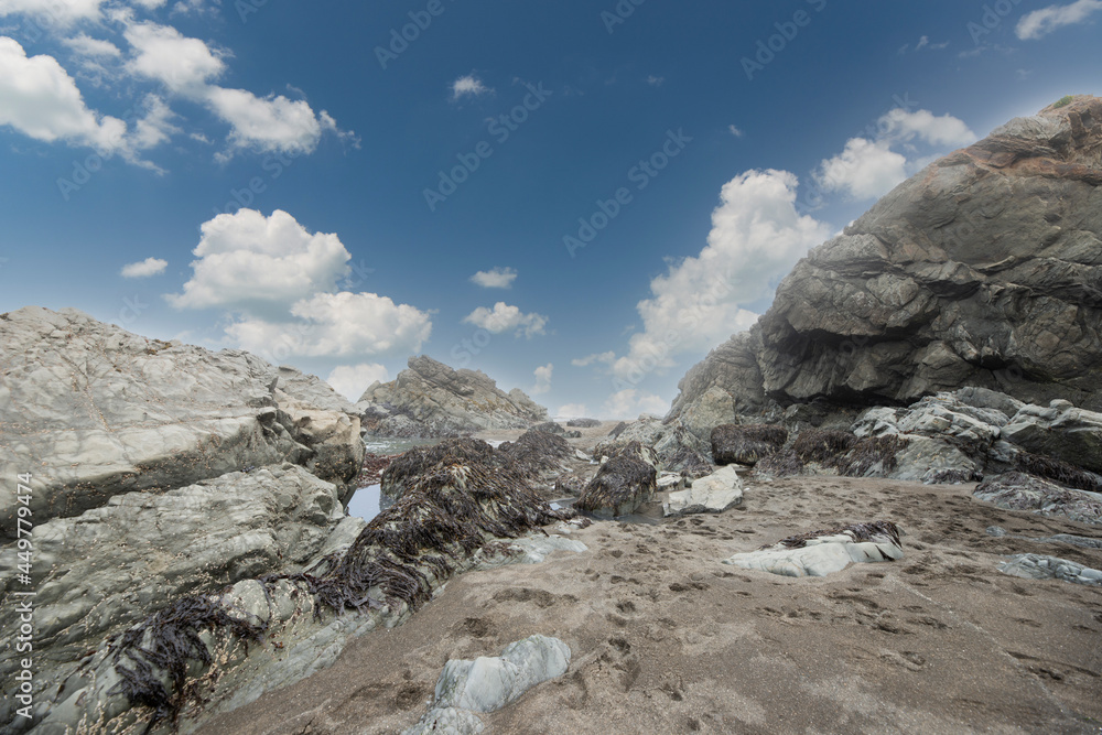 Rocky tide pools at low tide Northern California coast under beautiful cloud filled blue sky