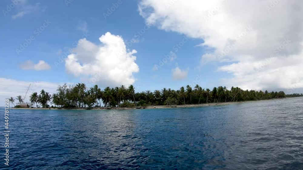 Boatride, boat drives by a tropical island with a wrecked sailboat and coconut palm trees on the beach