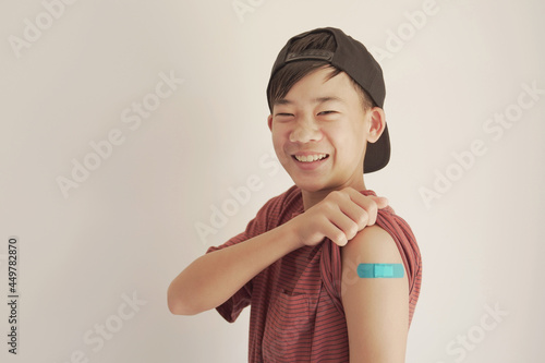 Fotografía Mixed Asian teen boy showing his arm with blue bandage after got vaccinated or