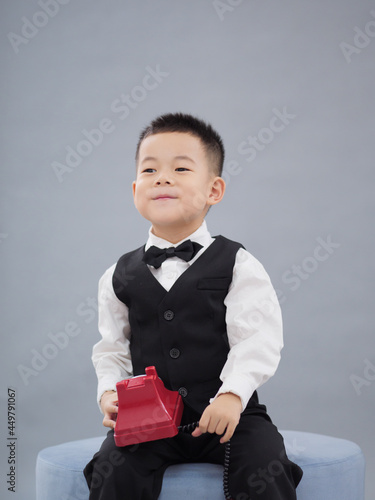 Asian little boy wearing a black vest, white shirt and bow tie