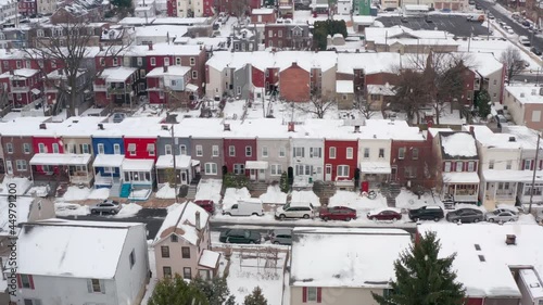 Aerial of snow falling on colorful rowhomes in winter. Downtown city houses in United States of America. Residential town community. photo