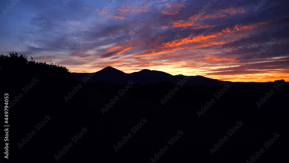 A silhouette of mountains with a fiery sunset in the background. A silhouette of mountains with a fiery sunset in the background.