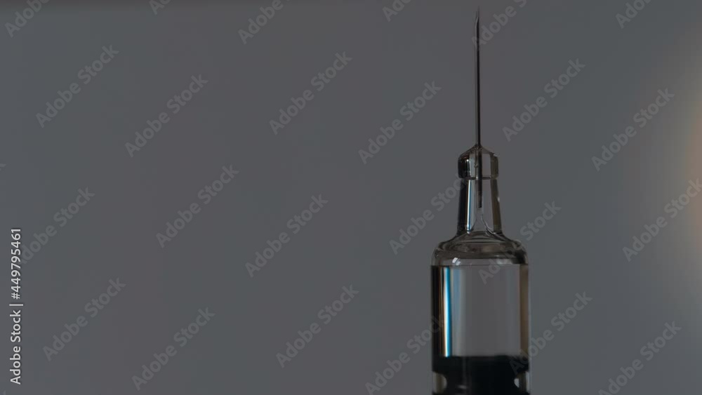 Glass modern syringe for vaccine injection glitters in colored light on a light background. Closeup. Macro Glass modern syringe for vaccine injection glitters in colored light on a light background. Closeup. Macro