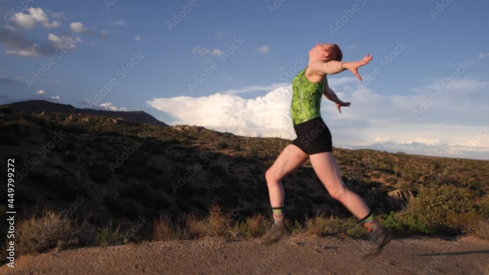 Acrobat jumps into the air in a brilliant pose with magnificent clouds behind her. Acrobat jumps into the air in a brilliant pose with magnificent clouds behind her.