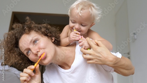 White toddler Learning how to enjoy brushing teeth with mom. Oral hygiene for babies