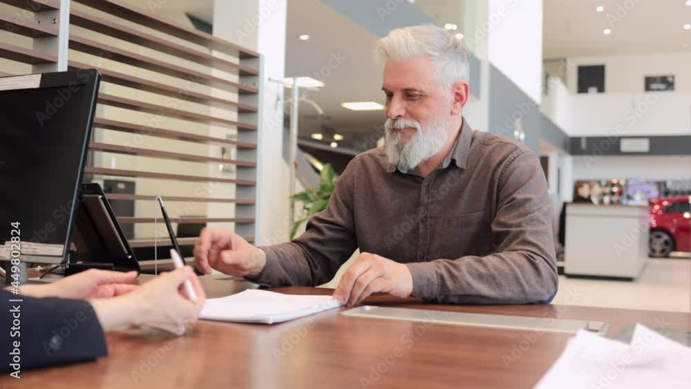 Man making deal and shaking hands while sitting at table in dealership office spbi.