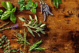 Fresh garden herbs, overhead flat lay shot on a rustic wooden background with copy space. Bunches of rosemary, thyme, lavender and various other aromatic plants