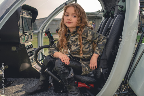 Tableau sur toile Dreamy tween girl sitting in open cockpit of helicopter