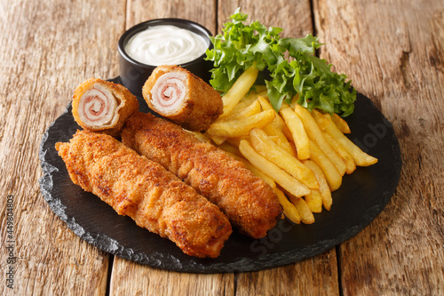 Flamenquin thin Pork Roll with Jamon served with French fries closeup in the slate plate on the table. Horizontal photo