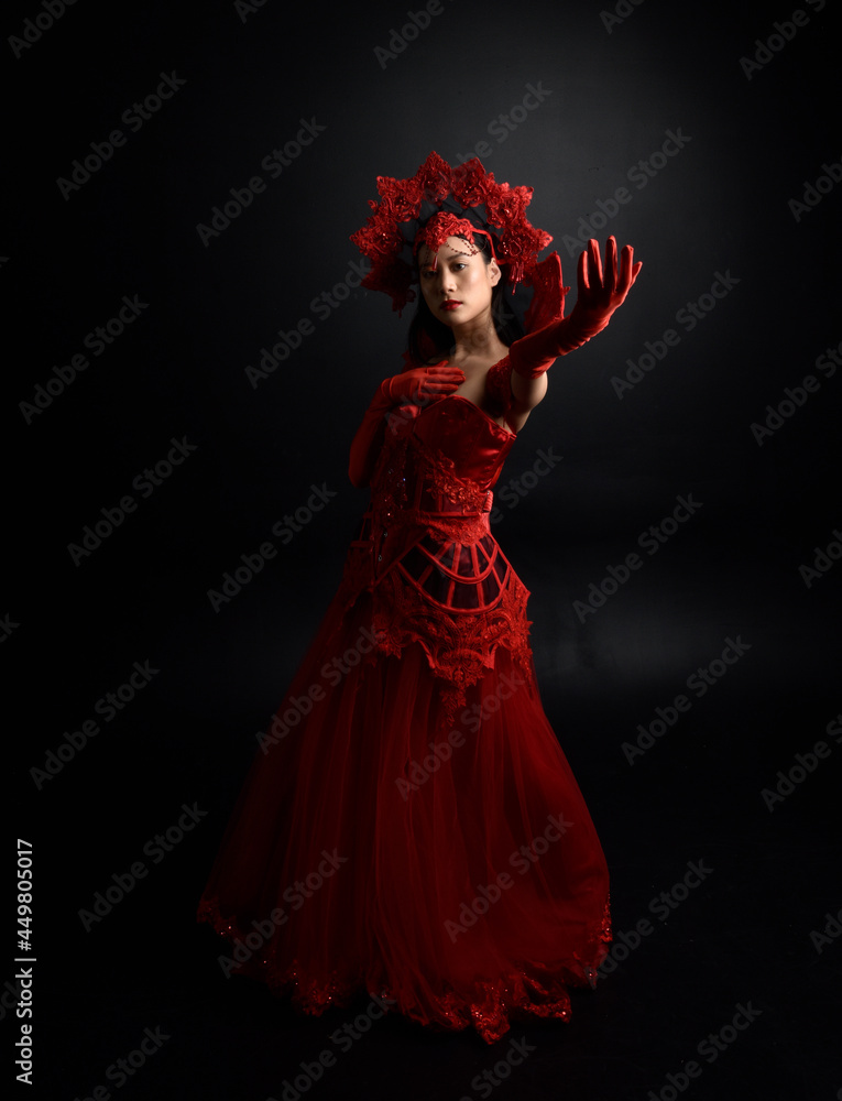 portrait of beautiful young asian woman wearing red corset, posing in gothic horror style with creative hand gestures isolated against studio background. portrait of beautiful young asian woman wearing red corset, posing in gothic horror style with creative hand gestures isolated against studio background.