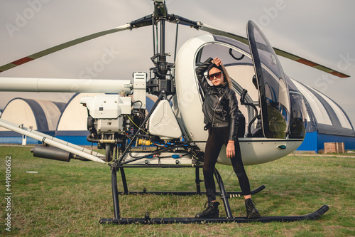 Tween girl in black clothes standing near helicopter photo