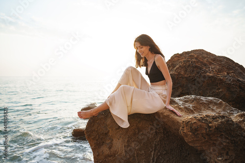 Woman traveler sitting near sea on cliff injoying view of sea and nature photo