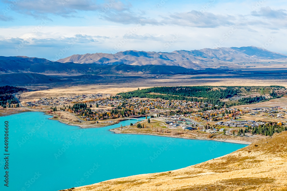 aerial view of a turquoise Lake Tekapo and a lovely Tekapo Town in Autumn, view from Mount John in Mackenzie Region, south island of New Zealand