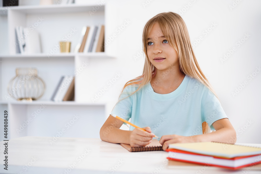 Teenage girl making notes in notepad, doing homework at table at home Teenage girl making notes in notepad, doing homework at table at home