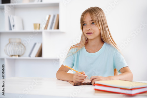 Teenage girl making notes in notepad  doing homework at table at home