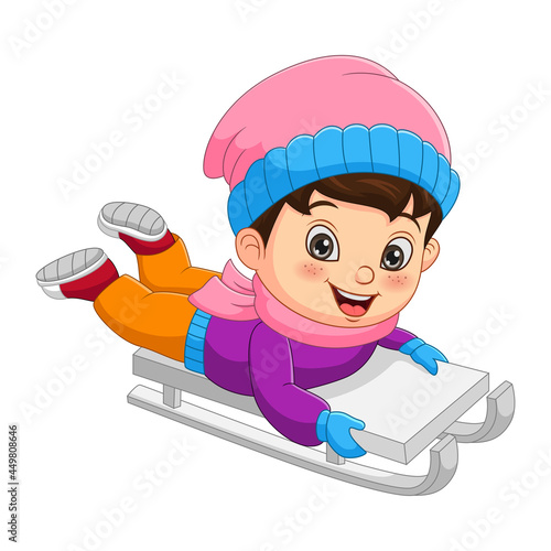 Cute little boy sledding down a hill