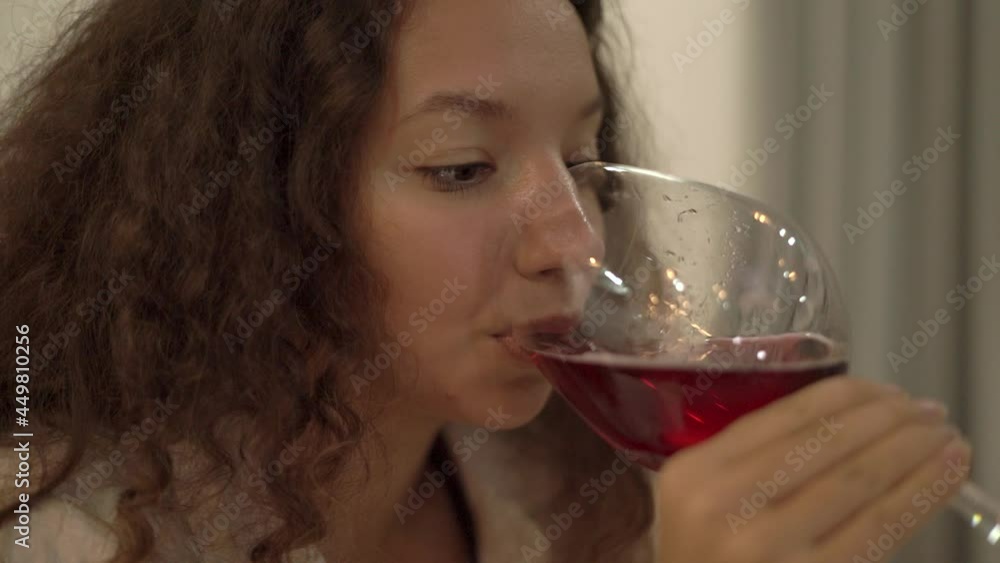 Young woman with curly hair tastes red wine. Mixed race lonely brunette holds stylish wineglass staying home in weekend evening closeup. Lady relaxes with wine glass Young woman with curly hair tastes red wine. Mixed race lonely brunette holds stylish wineglass staying home in weekend evening closeup. Lady relaxes with wine glass