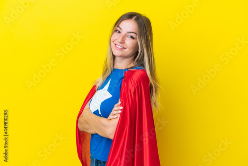 Super Hero Romanian woman isolated on yellow background with arms crossed and looking forward
